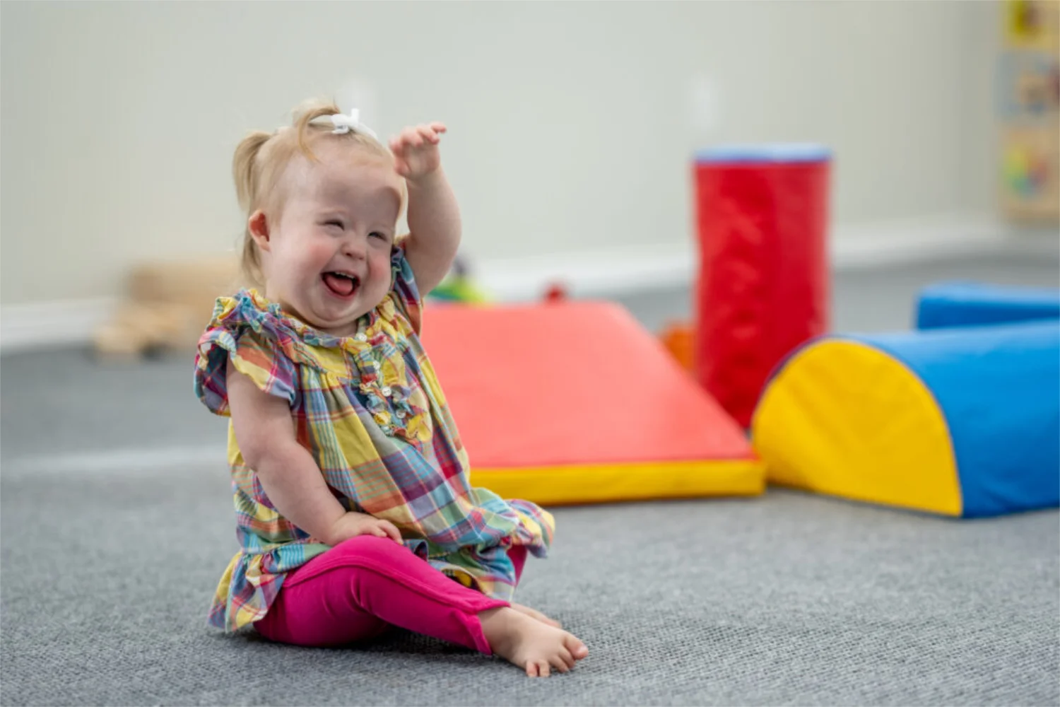 A toddler with Down syndrome laughing and playing