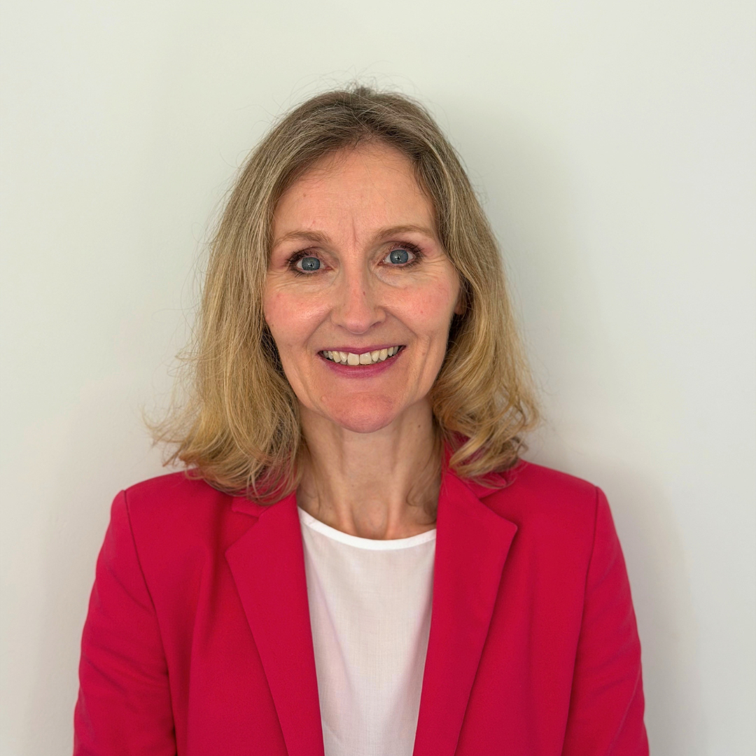 Sinead, a woman wearing a pink blazer, smiling